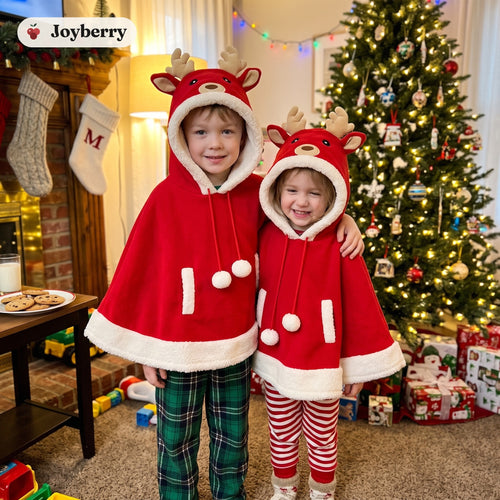 Brother and sister in matching Rudy reindeer capes by the Christmas tree